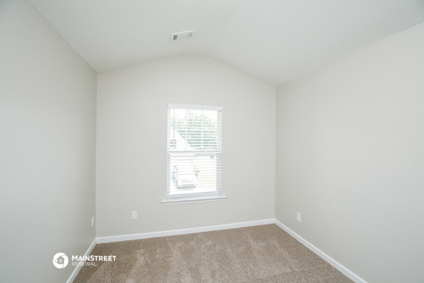 a bedroom with white walls and carpet and a window