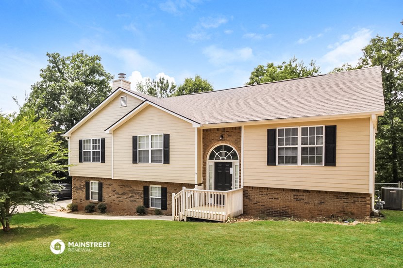 a tan house with black shutters and a front porch