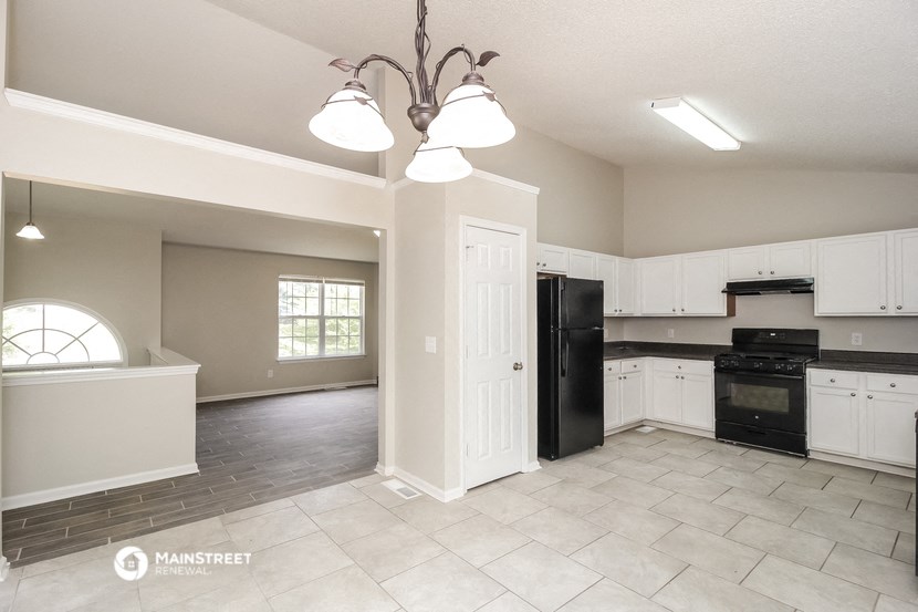 an empty kitchen with white cabinets and black appliances