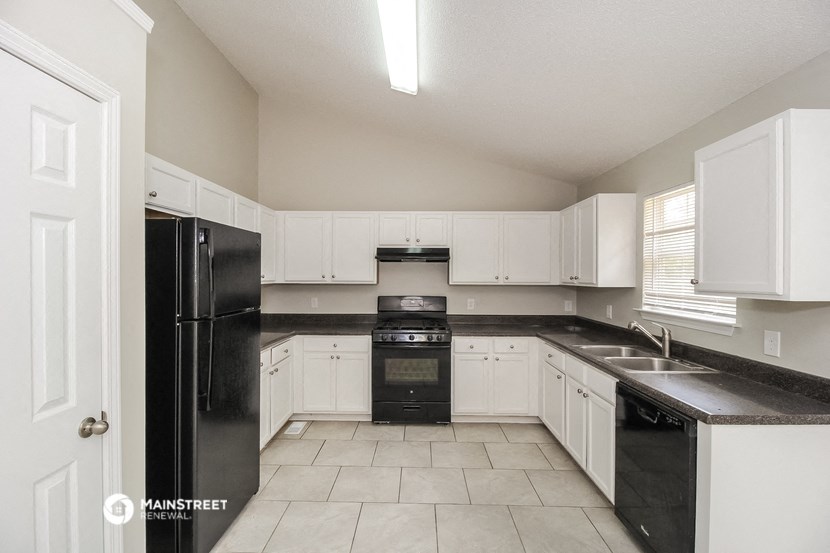an empty kitchen with black appliances and white cabinets