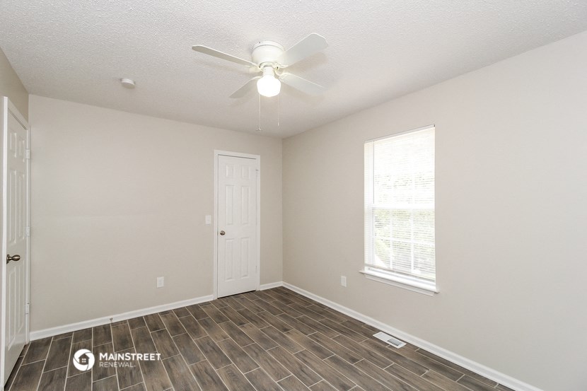 the spacious living room with a ceiling fan and wood flooring
