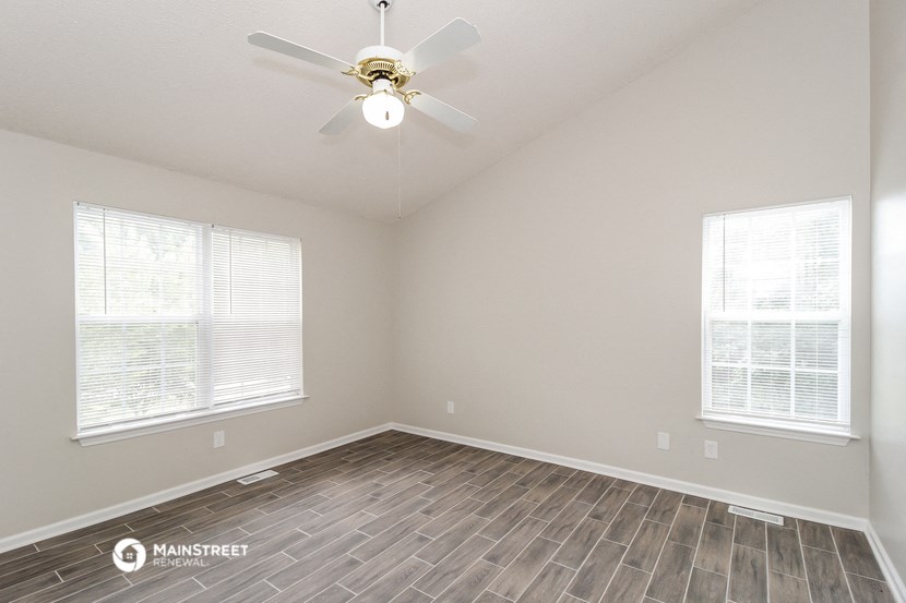 the spacious living room with wood flooring and a ceiling fan