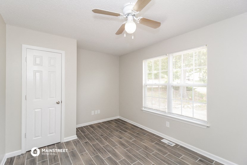 an empty room with a ceiling fan and a window