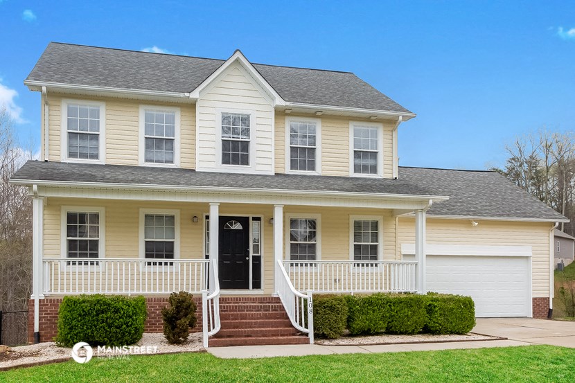 a yellow house with a white front porch and a black door