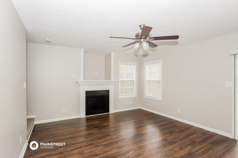 the spacious living room with a fireplace and a ceiling fan