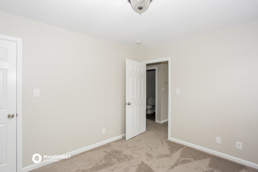 a bedroom with white walls and a door to a bathroom