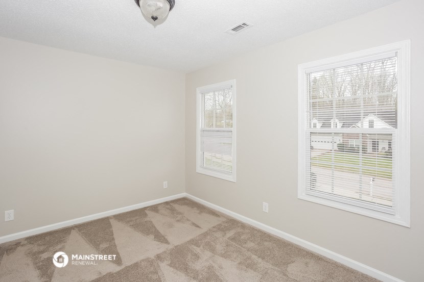 a bedroom with two windows and a carpeted floor