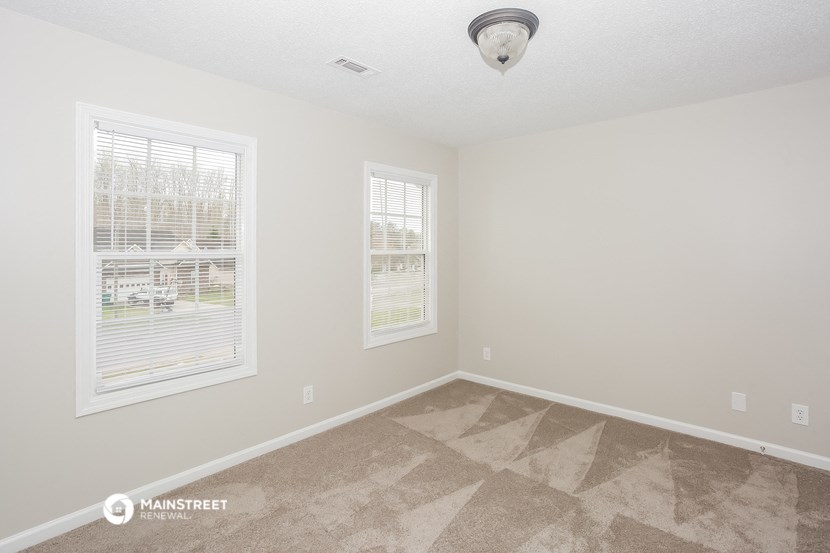 the spacious living room of a manufactured home with two windows