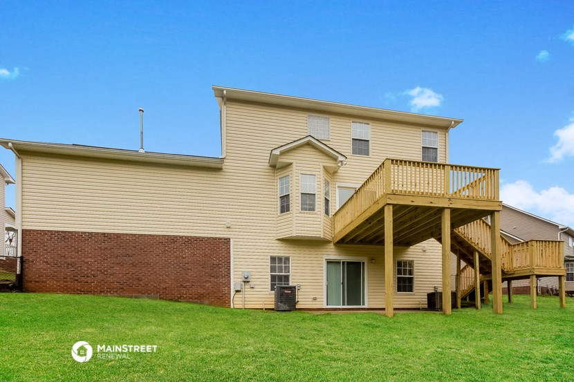 a yellow house with a deck and a brick wall