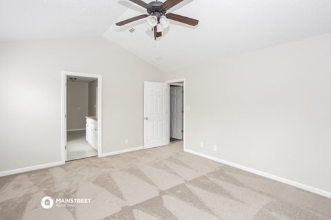 the spacious living room with carpet and a ceiling fan