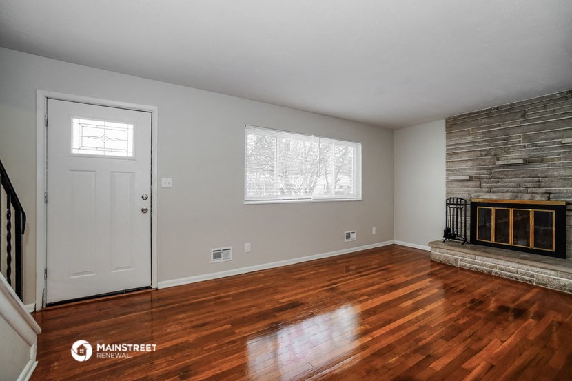 the living room with wood floors and a fireplace