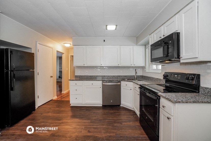 a renovated kitchen with white cabinets and black appliances