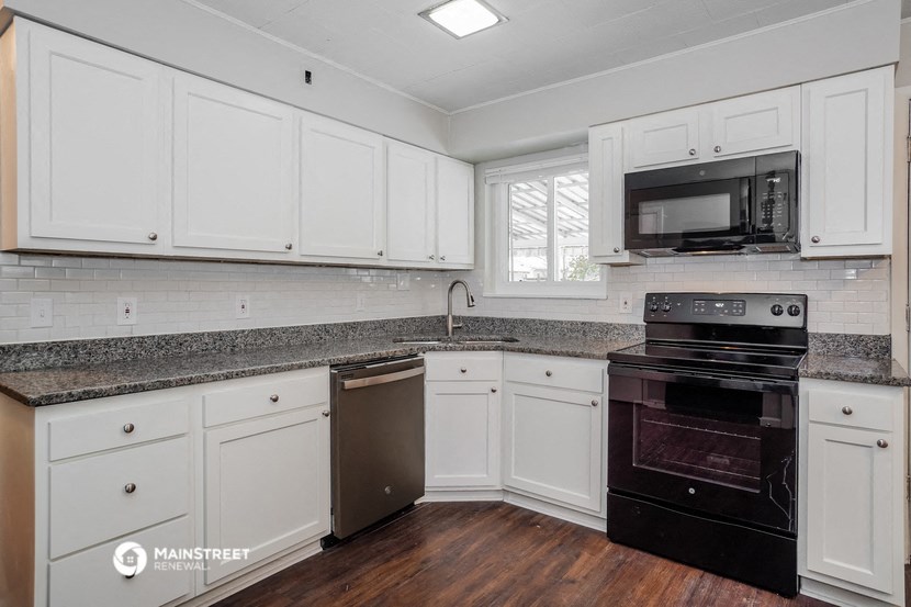 a kitchen with white cabinets and black appliances and a counter top