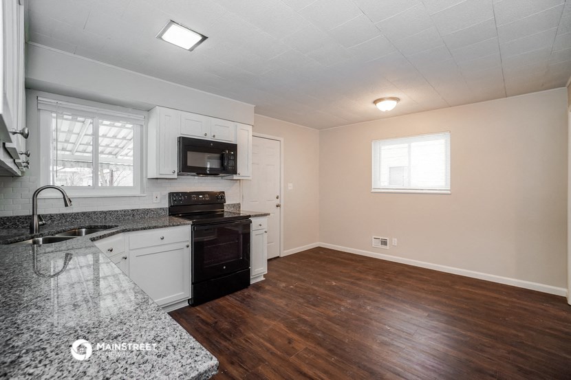 an empty kitchen with granite counter tops and white cabinets