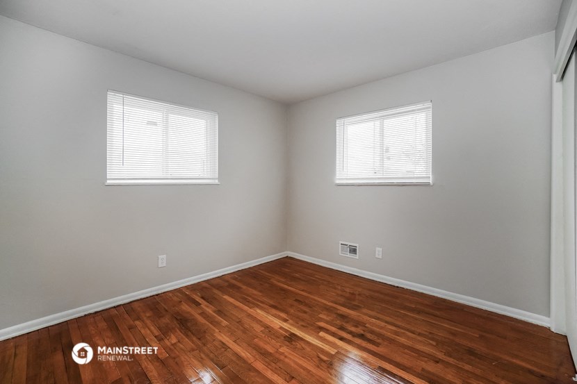 the living room with wood floors and two windows