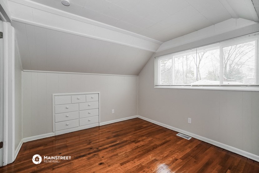 the bedroom of a house with wood floors and a large window