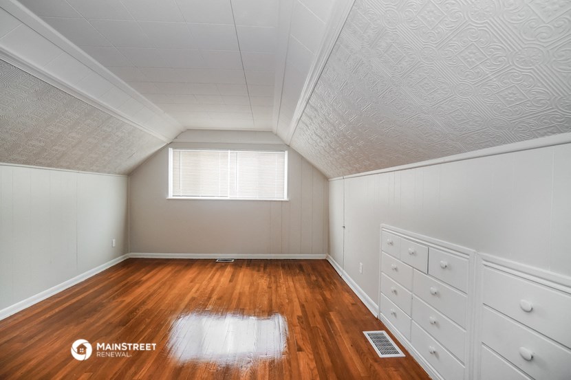 a bedroom with white cabinets and wood floors and a window