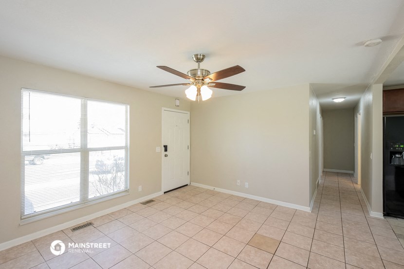 an empty living room with a ceiling fan and a large window