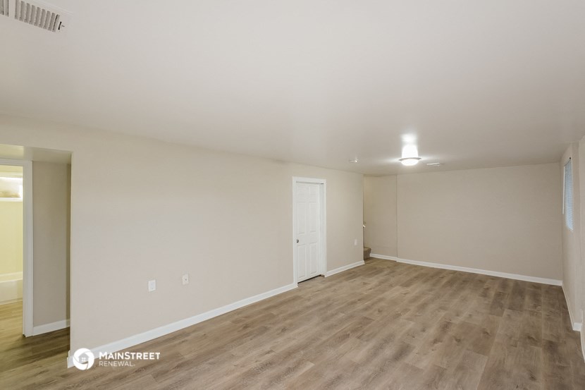 the spacious living room with wood flooring and white walls