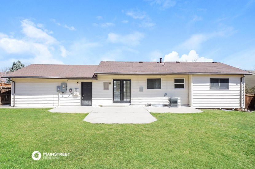 the front of a white house with a yard and grass