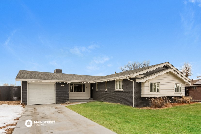 a white and black house with a yard and a blue sky