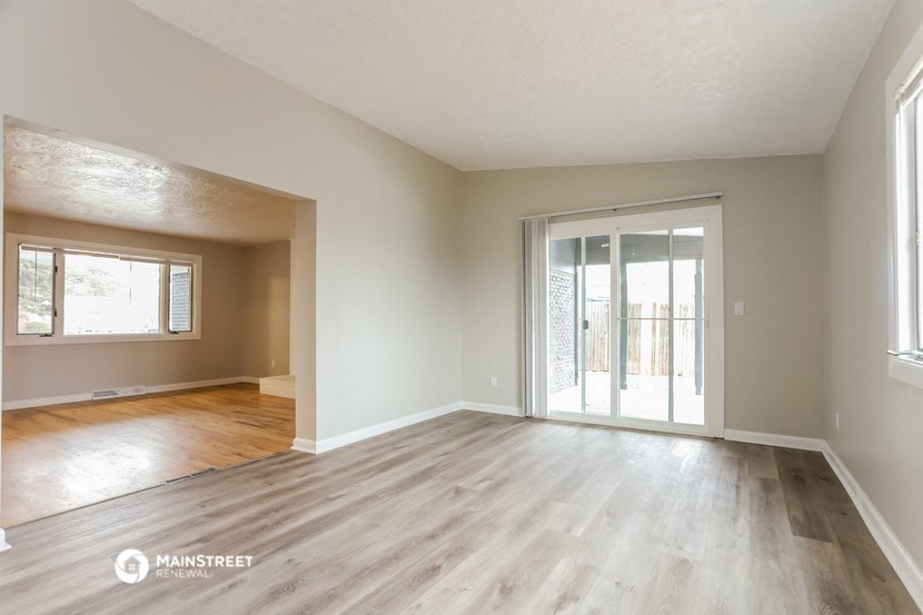 the living room and dining room of an empty house with wood flooring