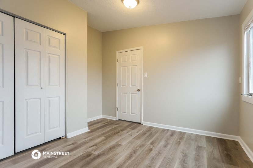 the living room of an apartment with white doors and wood flooring