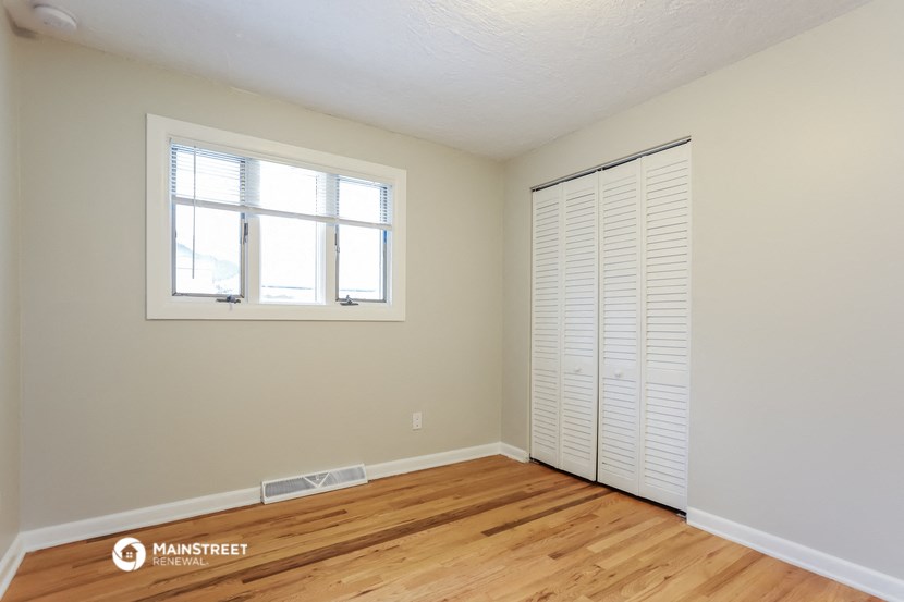 a bedroom with wood floors and a closet and a window