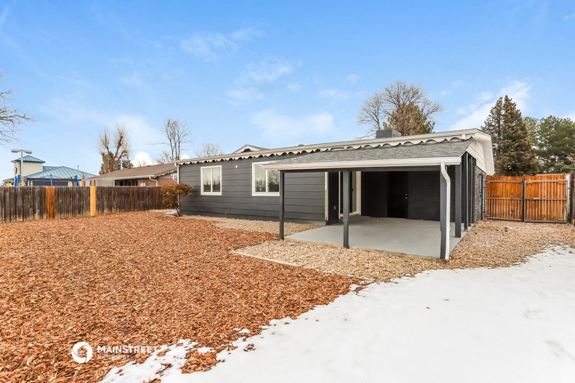 a small gray house with a garage and a yard in the snow