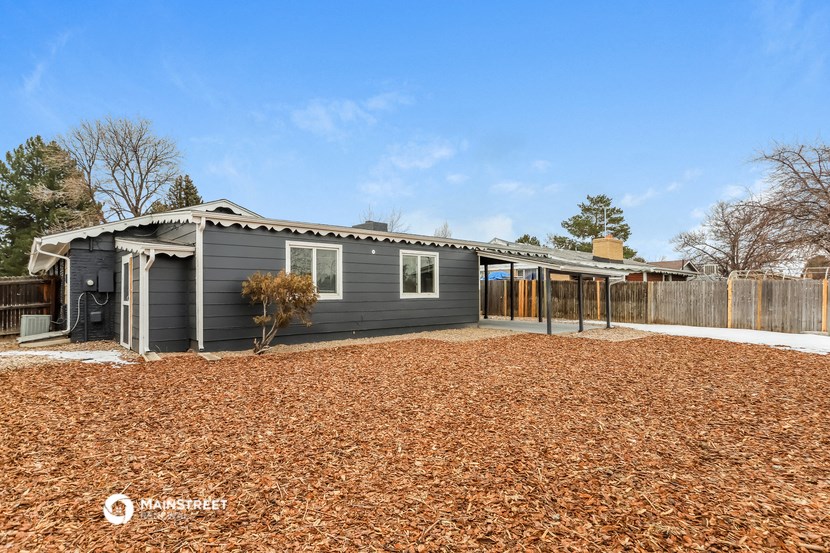 a small gray house with a yard and a fence