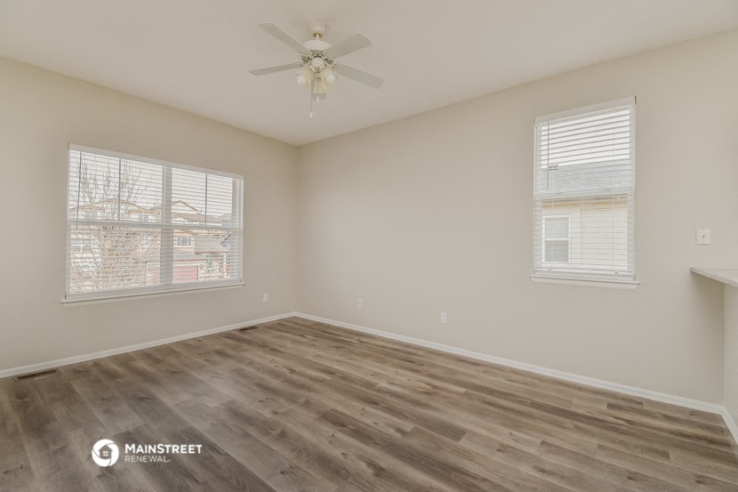 the spacious living room with wood flooring and a ceiling fan