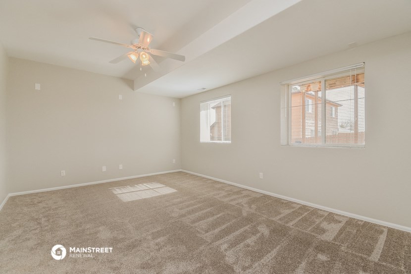 a spacious living room with carpet and a ceiling fan