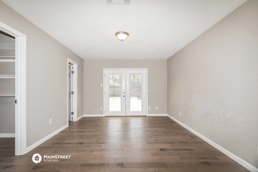 the spacious living room with hardwood flooring and white walls