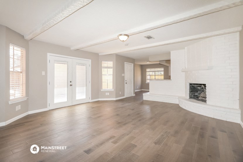 an empty living room with a fireplace and wood flooring