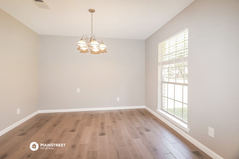 the spacious living room with wood flooring and a large window
