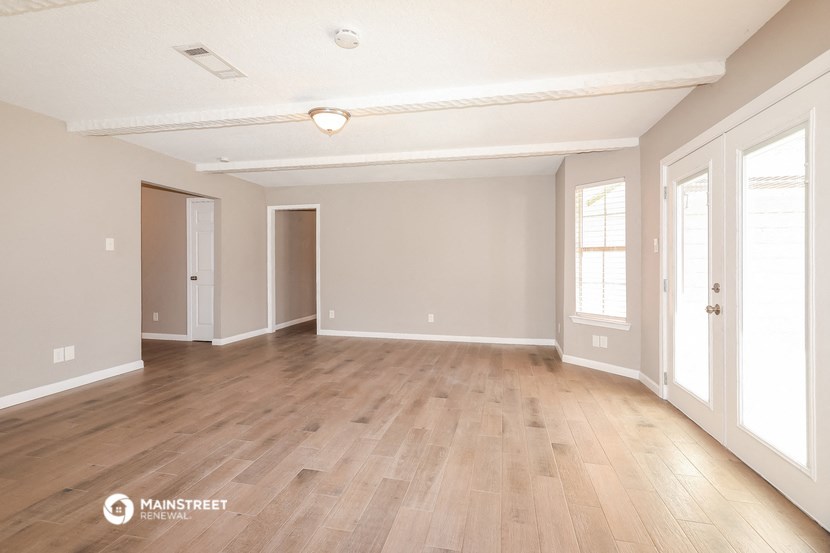 the spacious living room with wood floors and white walls