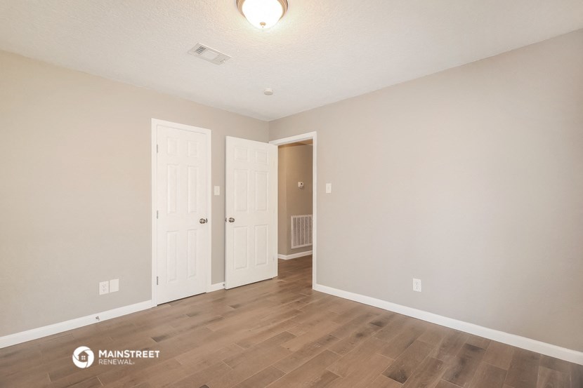 the living room of an apartment with white walls and wood flooring