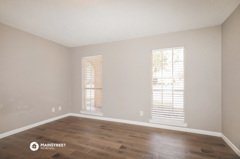 the spacious living room with wood flooring and two windows