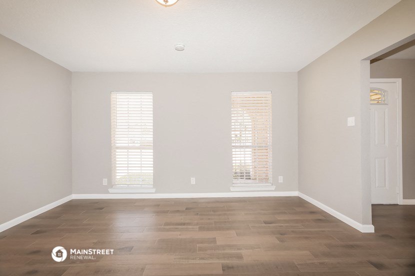 the spacious living room with wood flooring and two windows