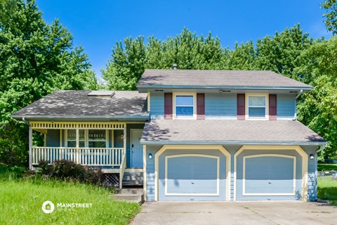 a blue and yellow house with a porch and white garage doors