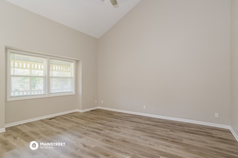 the spacious living room with wood flooring and a large window