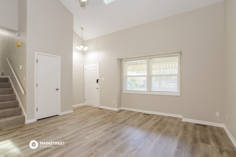the living room of an empty house with wooden floors and a staircase