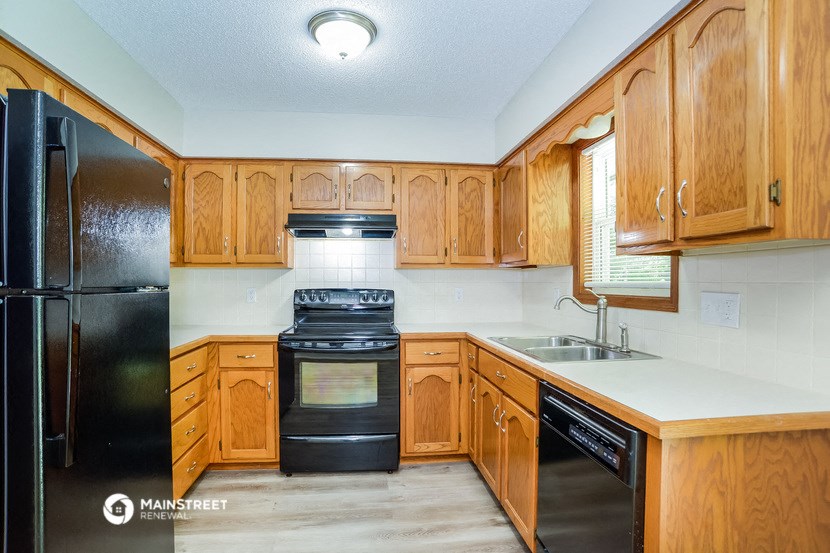 a kitchen with wooden cabinets and a black stove and refrigerator