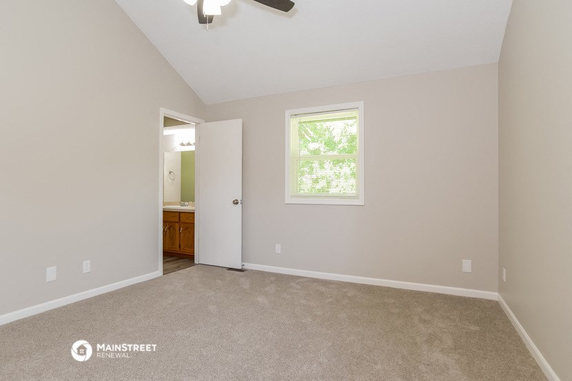 the master bedroom is spacious and has carpeted flooring and a ceiling fan