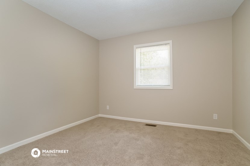a bedroom with beige carpet and a window