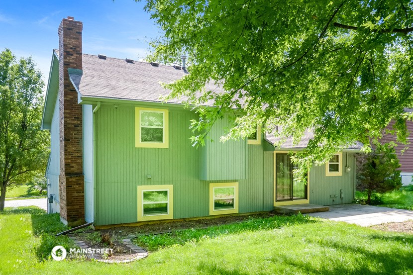 a green house with a tree in front of it
