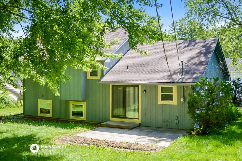 a green house with a porch and a tree