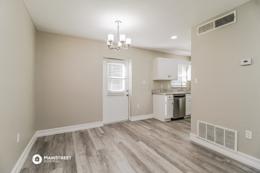 the living room and kitchen of an apartment with wood flooring