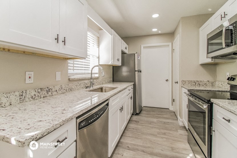 a kitchen with white cabinets and granite counter tops and stainless steel appliances