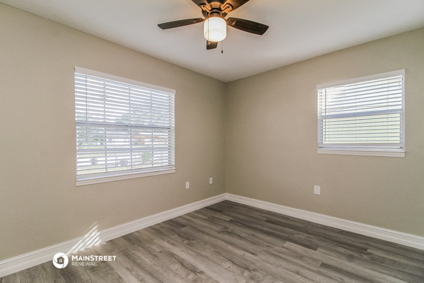 the interior of a bedroom with a ceiling fan and two windows